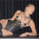 Lady Diyosa im schwarzen Korsett vor Vorhang Domina Lady Diyosa liegt seitlich in einem schwarzen Korsett vor einem dunklen Vorhang.