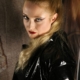 Porträt von Domina Lady Lia mit hohem blondem Pferdeschwanz, rotem Lippenstift und schwarzer Lackjacke.